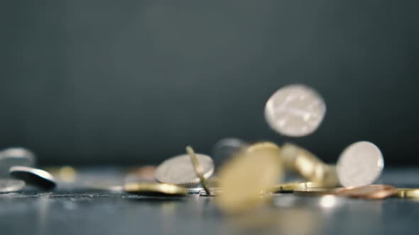 Coins of different countries and different denominations fall in slow motion on a black background
