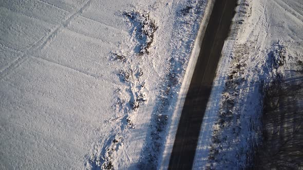 Aerial View of an Asphalt Road Surrounded By Snow in the Countryside