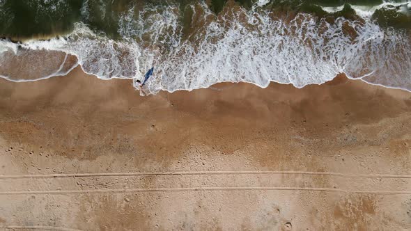 Woman in a White Shirt Runs Along a Sandy Beach