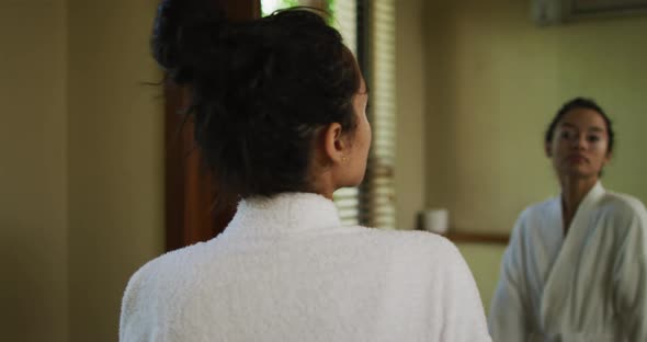 Relaxed biracial woman looking at herself in mirror and smiling