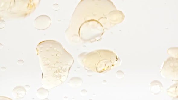 Slow Motion of Moving Yellow Golden Oil Air Bubbles in Water Rising Up on Light White Background