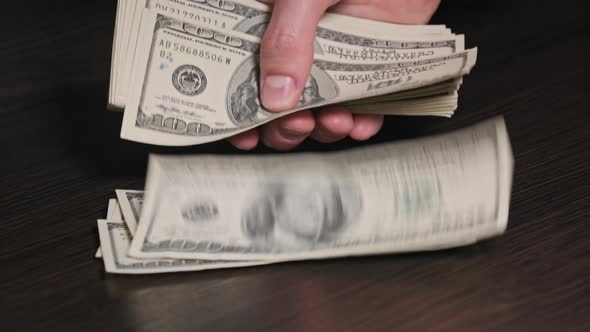 Counting Old Hundred Dollar Banknotes on a Black Wooden Table