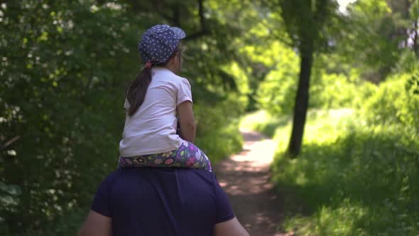 Daughter Rides Her Dad's Neck in the Park Day