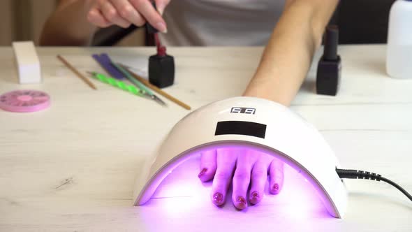 Girl Placed Hand Under an Nail Polish Curing Lamp and Waits for the Nail Polish to Harden