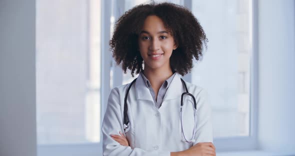 Young Ethnic Nurse Doctor Woman Standing in Clinic Happy Face Smiling with Crossed Arms Looking at