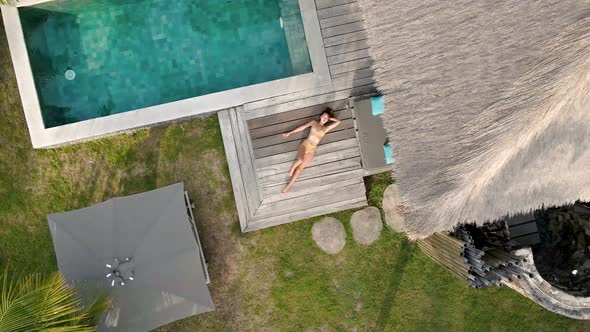 Girl lying and resting on terrace of luxury villa with pool during holidays on Gili Air,Indonesia.Ae