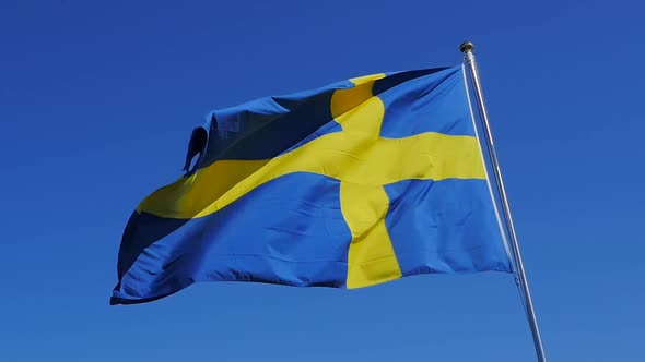 Close-up of the Swedish flag in slow-motion on a clear sunny day. The footage was shot in the region