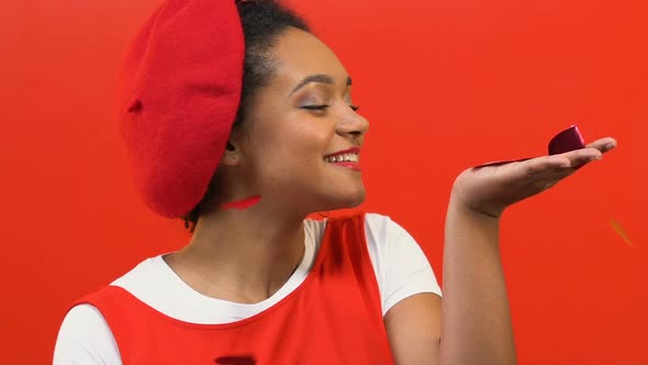 Female Teenager in Red Beret Taking in Hand Falling Heart-Shaped Confetti