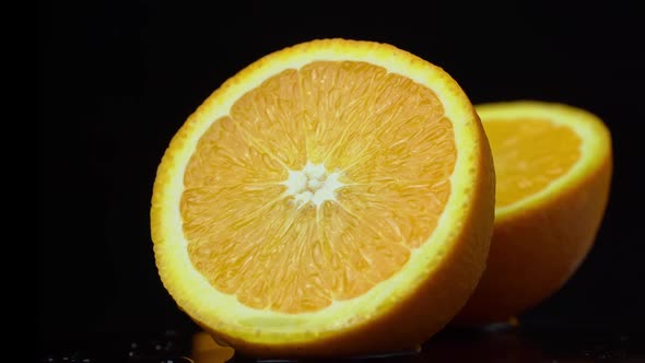 Half of a Juicy Orange Rotates in a Circle on a Black Background