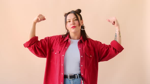 Strong powerful stylish woman with tattoo, raises arms and shows biceps. Feminism