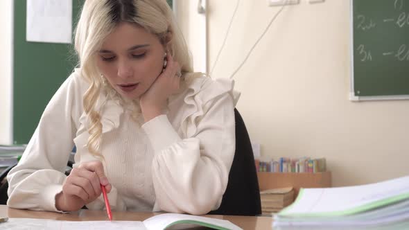 Woman School Teacher in Class Checks Notebooks with Homework