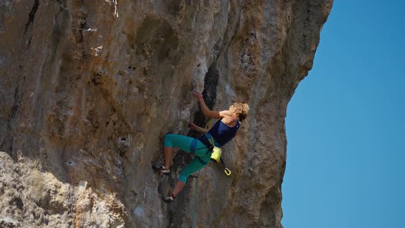 Strong Female Rock Climber Trying to Climb Hard Tough Rock Route on Overhanging Cliff