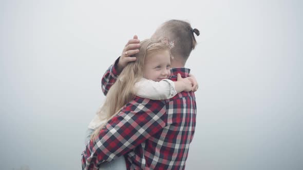 Happy Relaxed Little Cute Girl Hugging Man Smiling Enjoying Leisure with Parent Outdoors on Misty