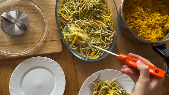 Young woman laying colored pasta on a plate