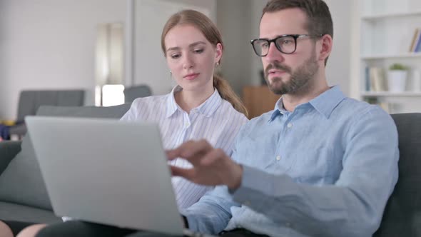 Serious Young Couple Using Laptop at Home