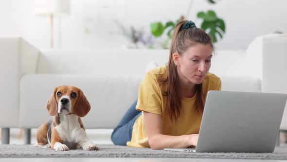 Woman Freelancer Typing Text on Laptop for Blog Lie on Floor with Dog Spbi
