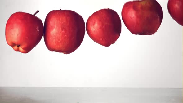 Super Slow Motion Red Apples Fall Into the Water with Splashes