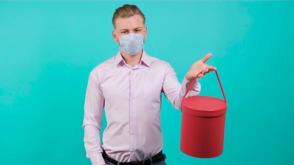 Man Wearing Face Mask While Giving a Box and Standing in the Studio.