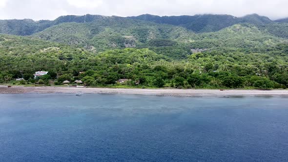 Aerial drone flying over beautiful coral reef ocean towards a remote secluded and rugged tropical is