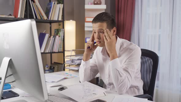 Young man with headache while working.