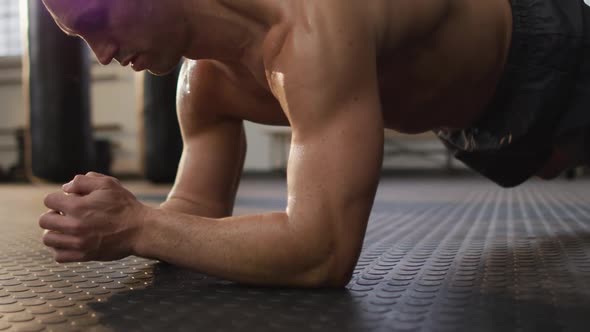 Caucasian muscular shirtless bald man exercising and doing plank