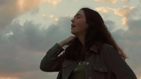 Portrait of a young beautiful smiling woman admiring the sunset. Bottom view.