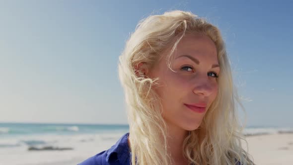 Woman standing on beach in the sunshine 4k