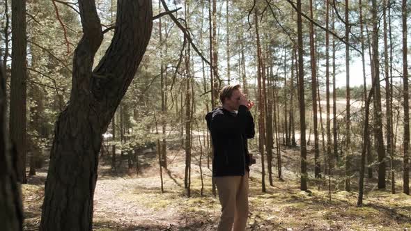 A Young Blond Photographer Takes Pictures in the Woods with a Film Camera