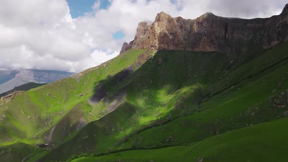 Rocky Cliff with Green Hills on Sunny Day