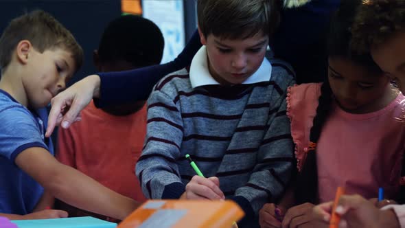 Teacher helping schoolkids with their homework in classroom