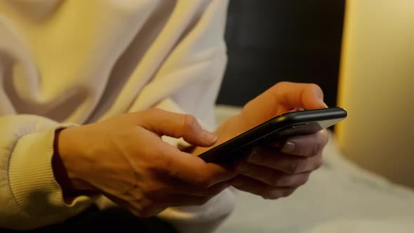 Close Up Shot of Woman Use of Smart Phone at Home in Yellow Light