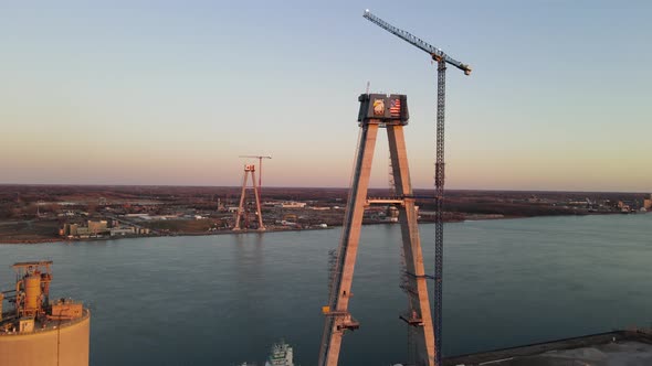 Forwarding aerial shot of the Gordie Howe Bridge under construction, Suspension tower with crane, De