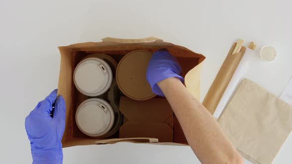 Hands in Gloves Packing Takeaway Food for Customer