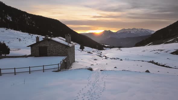 Smooth drone traveling through the snowy town of Cortals in Andorra, in the background the sunset be