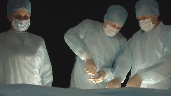 Three Surgeons, a Man and a Woman, Perform Surgery To Remove Prostate Adenoma and Varicocele