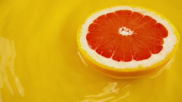 Rotating segment of ripe and juicy grapefruit on an orange background. Slow motion.