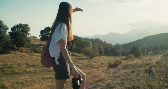 Female with Camera Climbs Mountain and Takes Picture of Scenery Enjoying a View