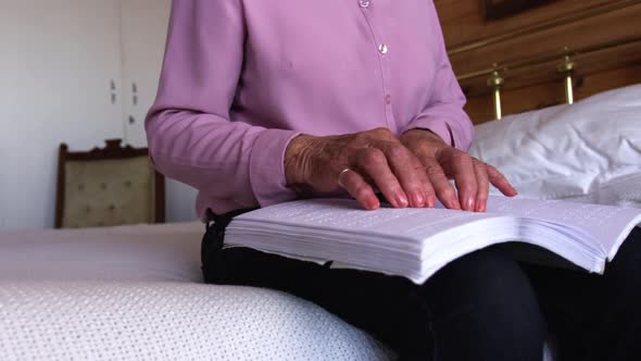 Woman reading a braille book in bedroom at home 4k