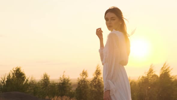 Portrait of Attractive Woman in Nature at Sunrise or Sunset Sun Shine in Camera