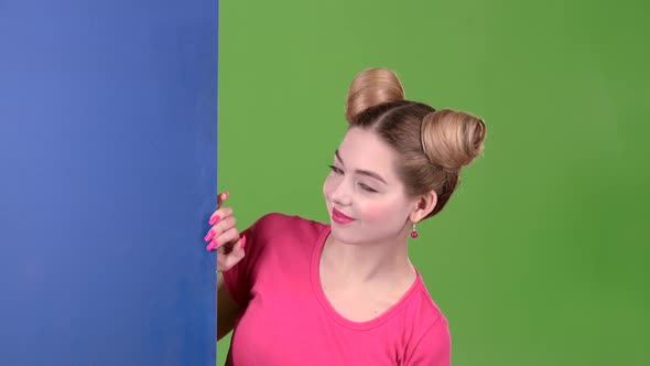 Teenager Peeks Out From Behind a Blue Board and Shows a Thumbs Up. Green Screen. Slow Motion