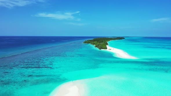 Wide flying island view of a paradise sunny white sand beach and blue water background in 4K