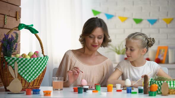 Mom Teaching Daughter How to Color Easter Eggs