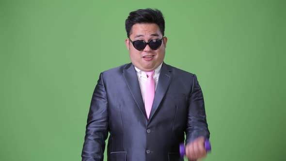 Young Handsome Overweight Asian Businessman Against Green Background