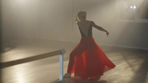 Elegant Female Ballet Dancer in Scarlet Red Skirt Rehearsing in Backlit Fog Indoors