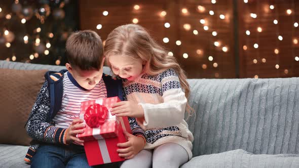 Amazed Boy and Girl Opening Red Festive Gift Box at Christmas Tree Decoration