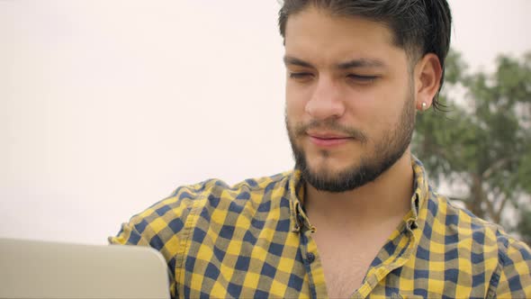 Handsome man siting on stairs using laptop outdoors