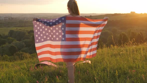 Happy Young Woman Posing with USA National Flag Standing Outdoors at Sunset