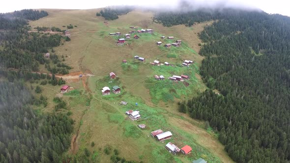 Forested Mountain Village Houses Through the Clouds in Grassland