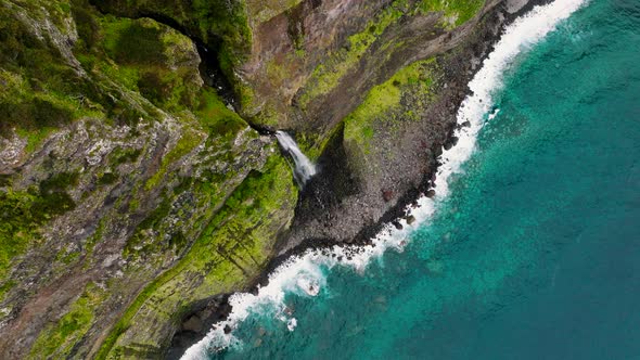 Dramatic overhead view of Veu da Noiva waterfall on rocky coastline, Seixal