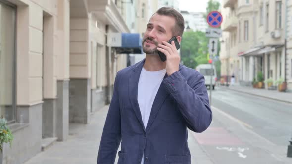 Man Talking on Phone While Walking Down the Street